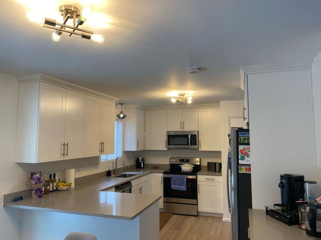 Modern kitchen with white cabinets, stainless steel appliances, and sleek countertops.