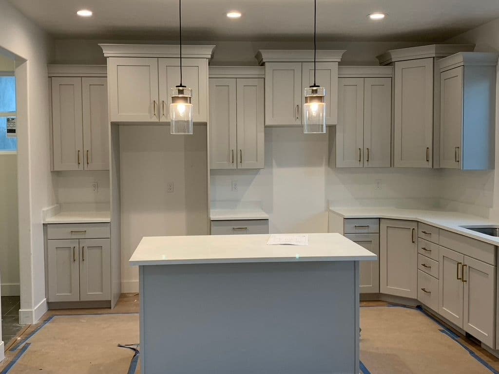 Modern kitchen design with light gray cabinetry, white countertop, and pendant lighting.