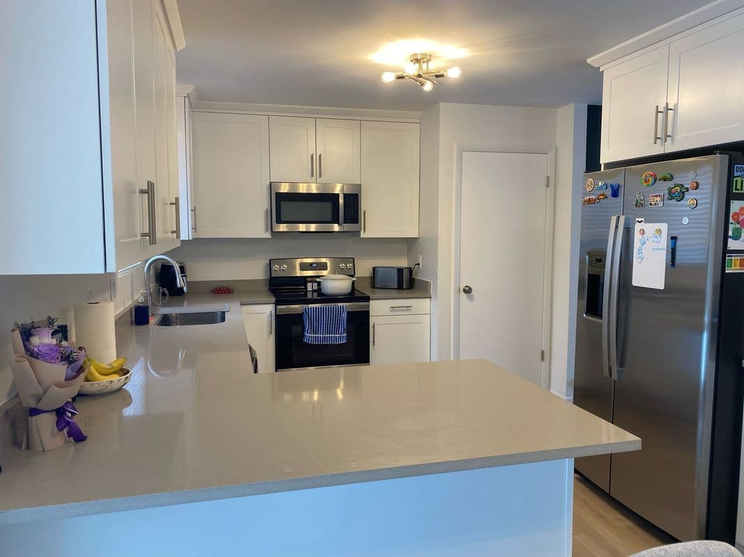 Modern kitchen with stainless steel appliances, white cabinetry, and a clean countertop.