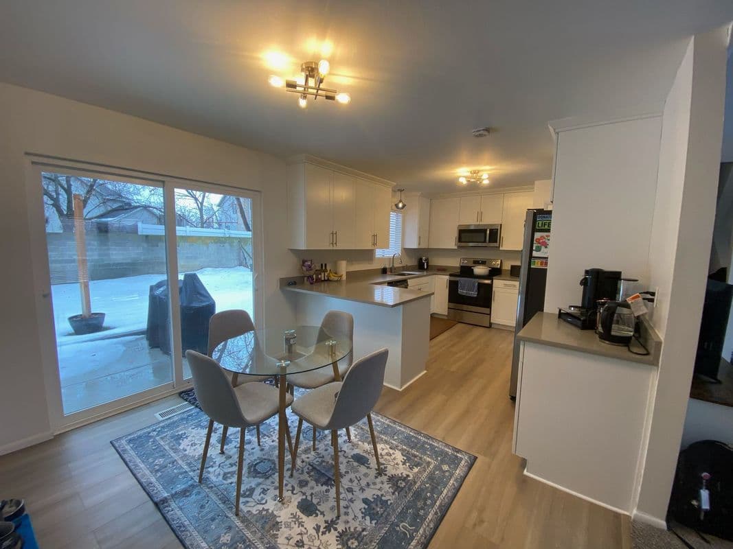Modern kitchen with dining area, large windows, and contemporary appliances. Bright and inviting space.