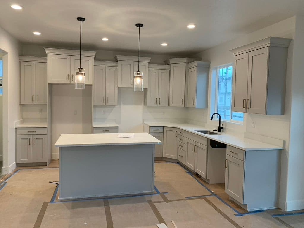 Modern kitchen with gray cabinetry, white countertops, pendant lights, and open layout.