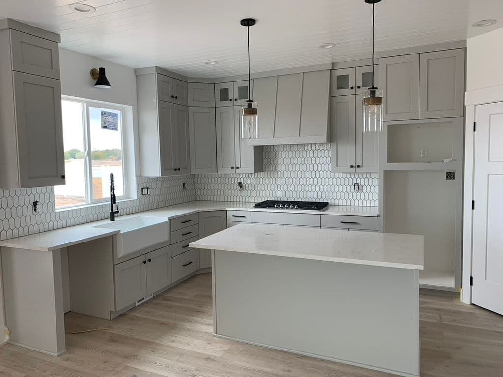 Modern kitchen design with gray cabinets, white countertops, and hexagon tile backsplash.