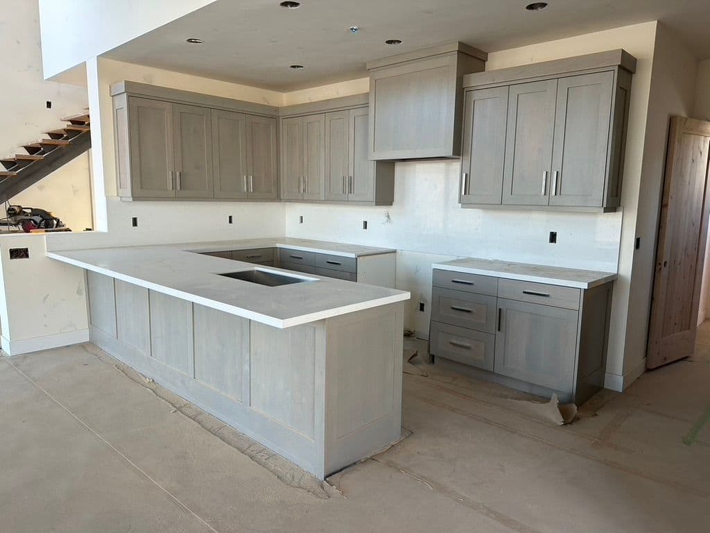 Modern kitchen design featuring light gray cabinets and a central island with a sink.