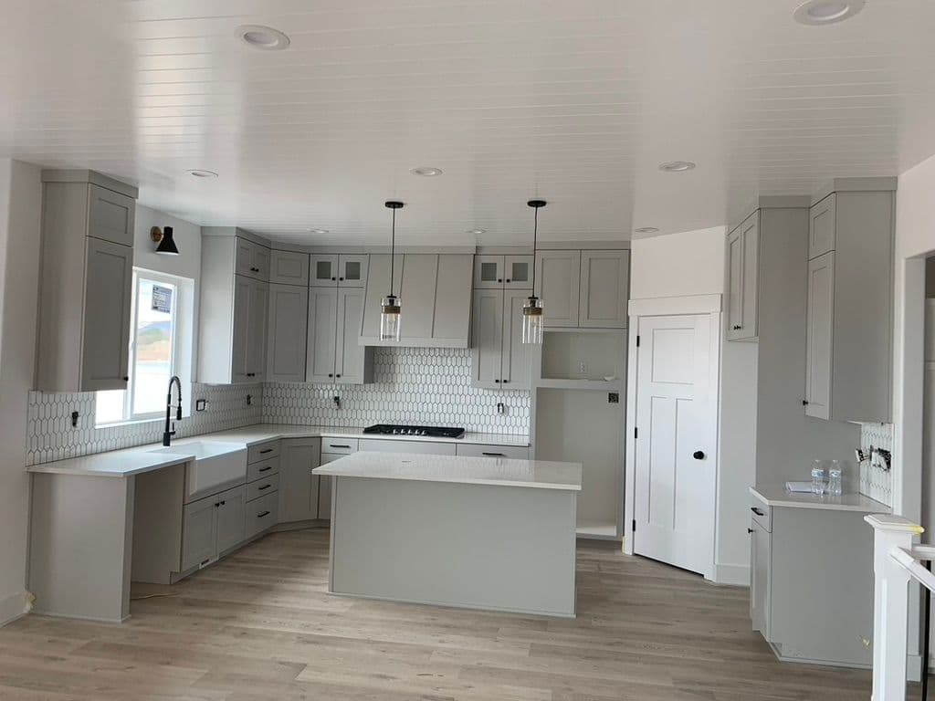 Modern kitchen with gray cabinets, marble countertop, and stylish pendant lights. Bright and spacious.