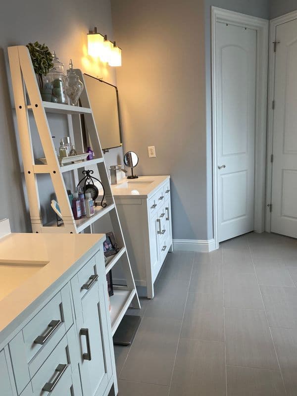 Modern bathroom with white cabinets, stylish shelving, and soft lighting illuminating the space.