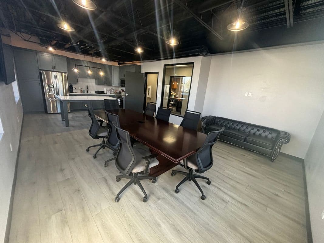 Modern conference room with a wooden table, ergonomic chairs, and a stylish couch.