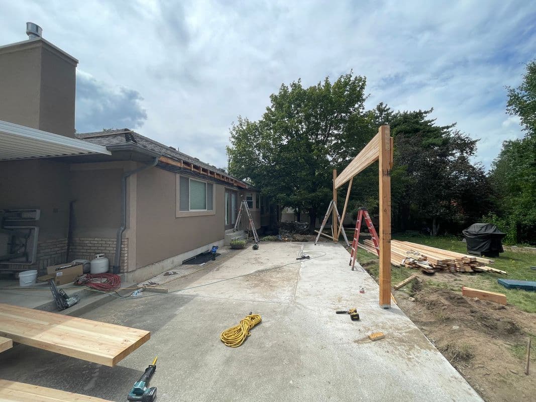 Construction site with wooden framework, tools, and materials against a cloudy sky.