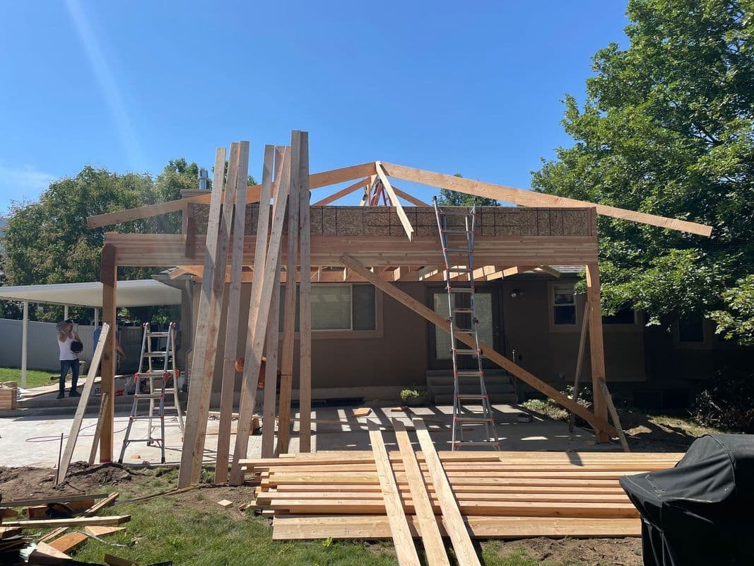 Home construction project showing wooden framework and materials under a blue sky.