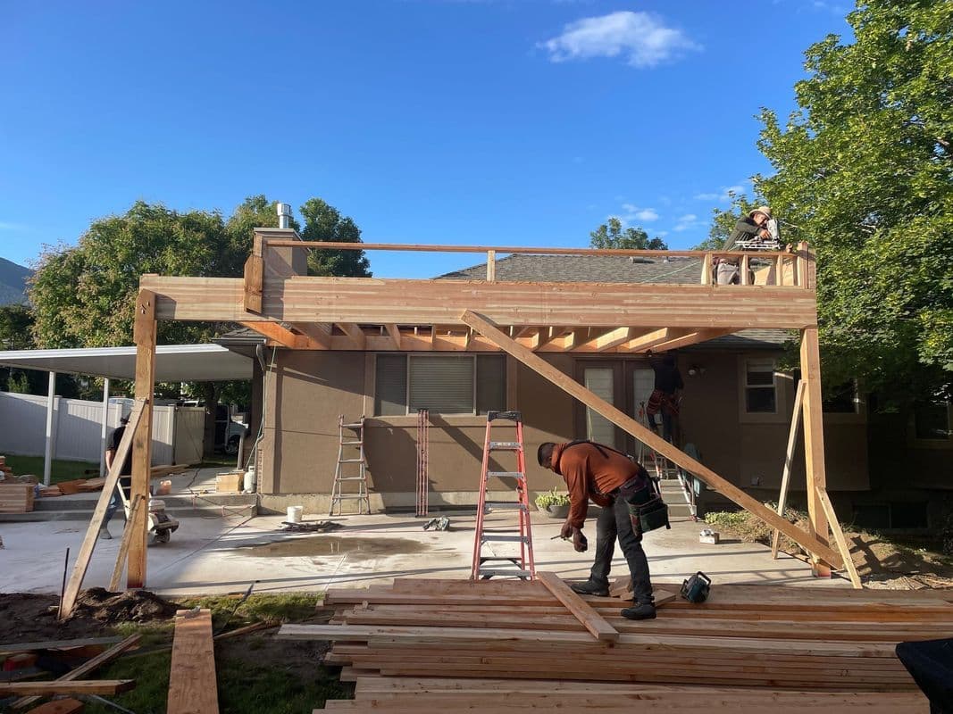 Construction workers building a wooden deck extension on a residential home.